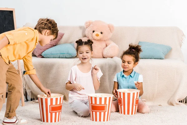 Adorables niños multiétnicos comiendo palomitas de maíz juntos - foto de stock