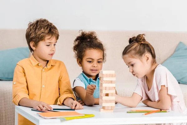 Mignons petits enfants multiraciaux jouant avec des blocs de bois sur la table — Photo de stock