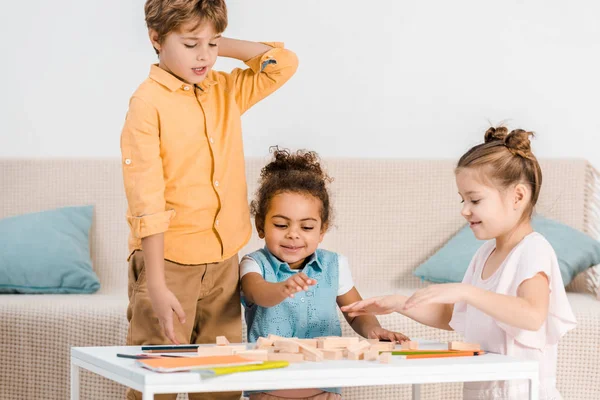 Liebenswerte multiethnische Kinder, die mit Holzklötzen auf dem Tisch spielen — Stockfoto