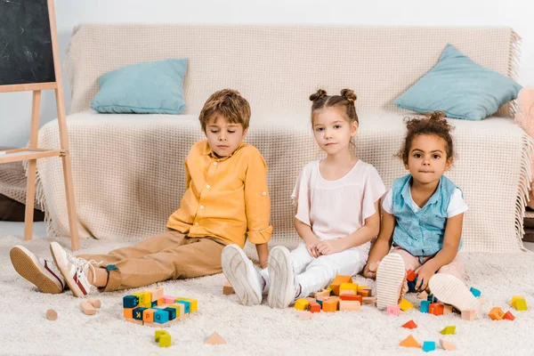 Mignon enfants multiethniques jouer avec des cubes colorés et regarder la caméra — Photo de stock