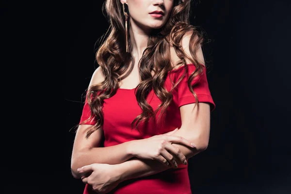 Vista ritagliata di donna in abito rosso in posa con le braccia incrociate isolato su nero — Foto stock