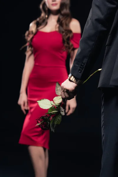 Abgeschnittene Ansicht von Mann mit Rose und Frau im roten Kleid auf Hintergrund isoliert auf schwarz — Stockfoto