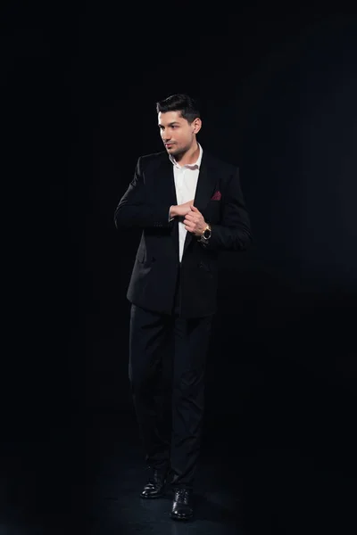 Hombre guapo posando en traje aislado en negro - foto de stock