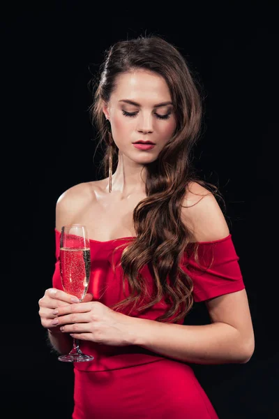 Hermosa mujer en vestido rojo sosteniendo copa de champán aislado en negro - foto de stock