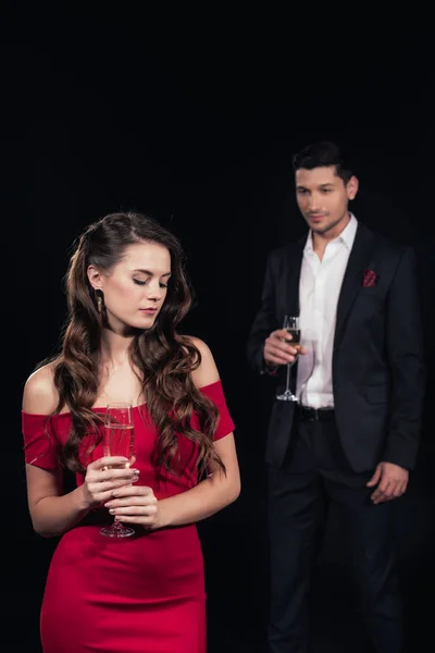 Beautiful couple in formal wear holding champagne glasses isolated on black — Stock Photo