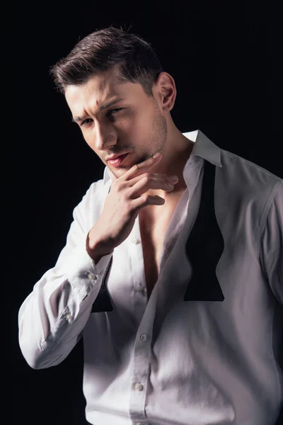 Homme en chemise blanche regardant caméra, toucher le menton et posant isolé sur noir — Photo de stock