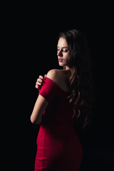 Приваблива жінка в червоній сукні з закритими очима позує ізольовано на чорному — стокове фото