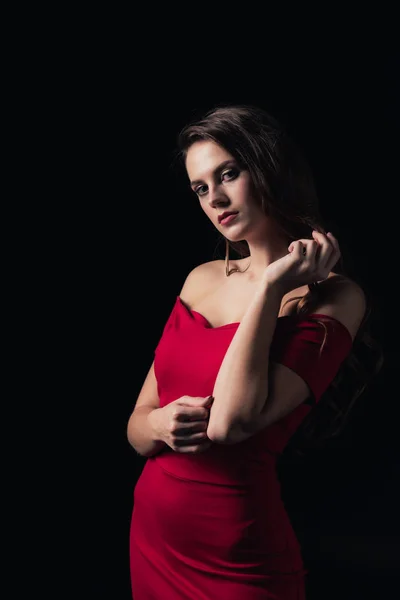 Bela mulher em vestido vermelho olhando para a câmera e posando isolado no preto — Fotografia de Stock