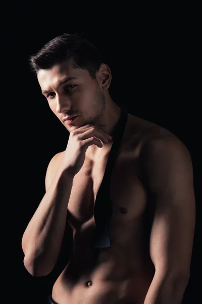 Shirtless man posing, looking at camera and touching chin isolated on black — Stock Photo