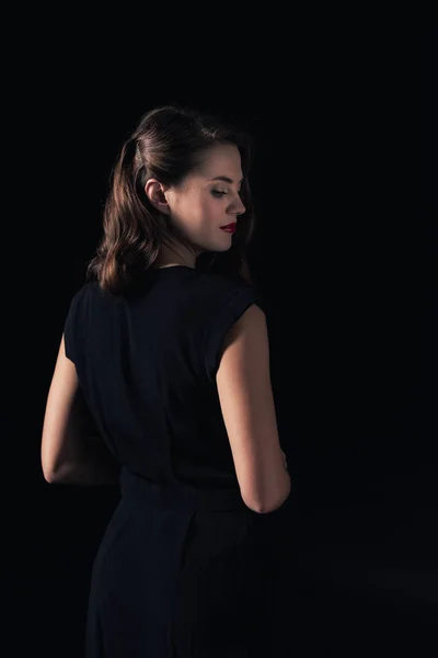 Visão traseira da mulher bonita no vestido posando isolado no preto — Fotografia de Stock
