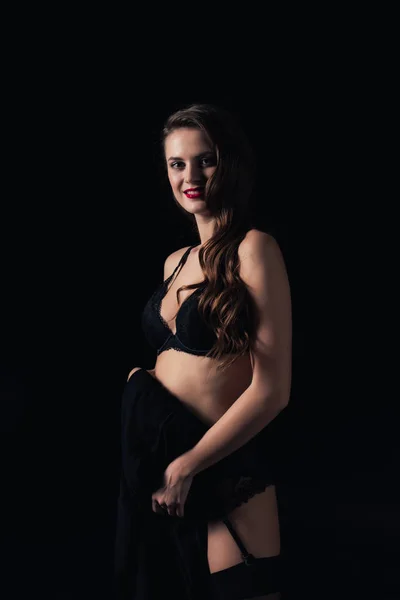 Femme souriante regardant la caméra et posant en lingerie isolée sur noir — Photo de stock