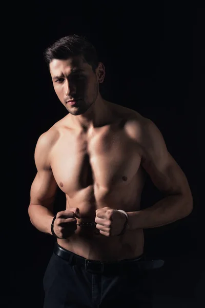 Handsome shirtless man in handcuffs looking at camera isolated on black — Stock Photo