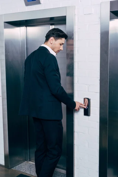 Uomo in tuta nera premendo pulsante ascensore — Foto stock