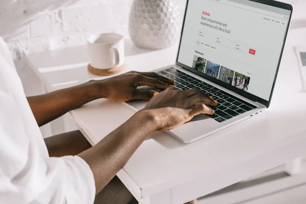 Ausgeschnittene Ansicht einer Afroamerikanerin, die auf Laptop mit Airbnb-Website tippt — Stockfoto