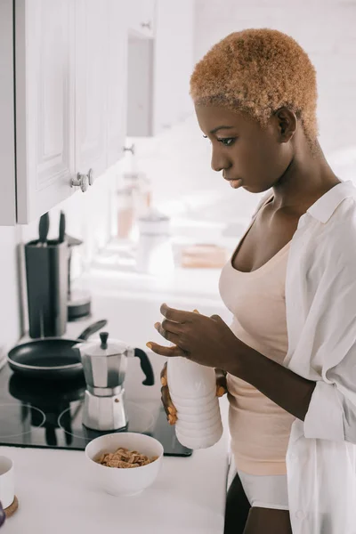 Thoughtful african american woman preparing breakfast in white kitchen — Stock Photo