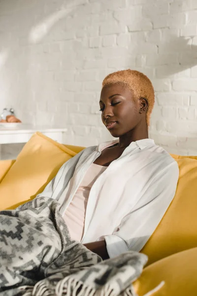 Schöne afrikanisch-amerikanische Frau entspannt auf gelbem Sofa — Stockfoto
