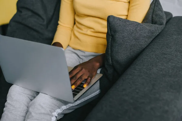 Обрізаний вид афроамериканської жінки, що використовує ноутбук у вітальні — стокове фото