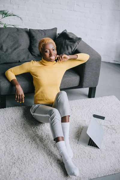 Приваблива афроамериканська жінка сидить біля дивана у вітальні — стокове фото