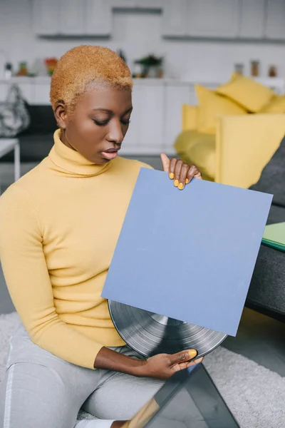 Selective focus of african american woman with short hair holding vinyl record — Stock Photo