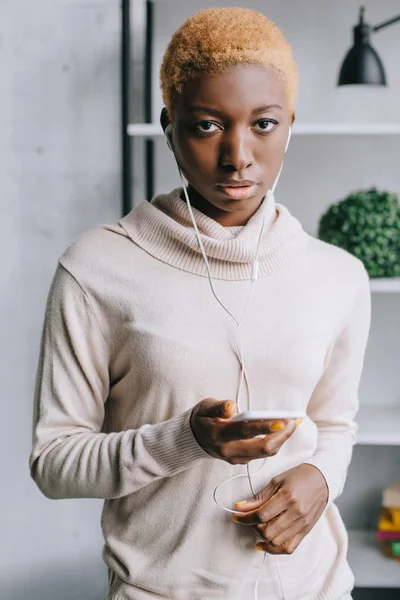 Selective focus of african american woman listening music in earphones — Stock Photo