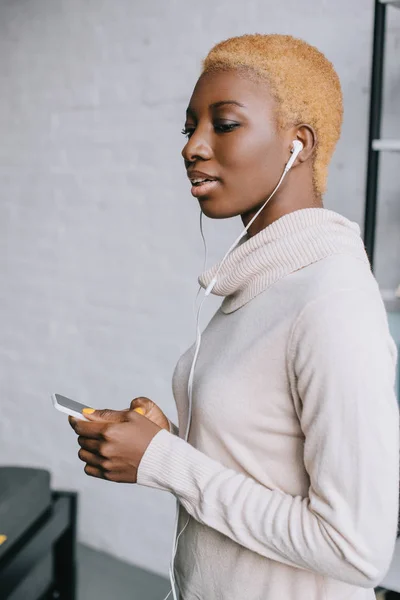 Selektiver Fokus einer verträumten afrikanisch-amerikanischen Frau, die Musik im Kopfhörer hört — Stockfoto
