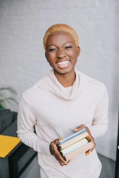 Fröhliche afrikanisch-amerikanische Frau hält Bücher in den Händen — Stockfoto