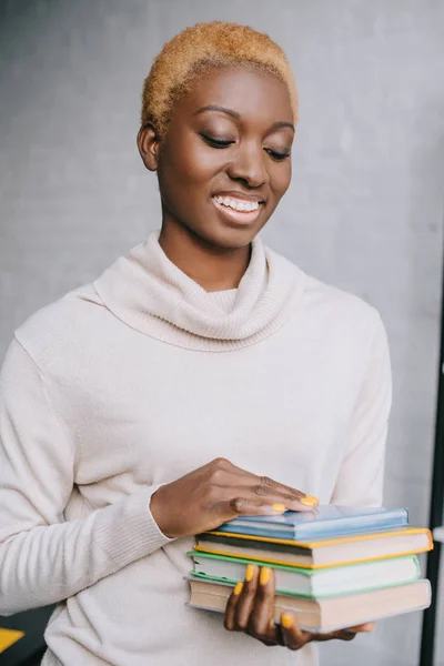 Selektiver Fokus einer fröhlichen afrikanisch-amerikanischen Frau, die Bücher in den Händen hält — Stockfoto