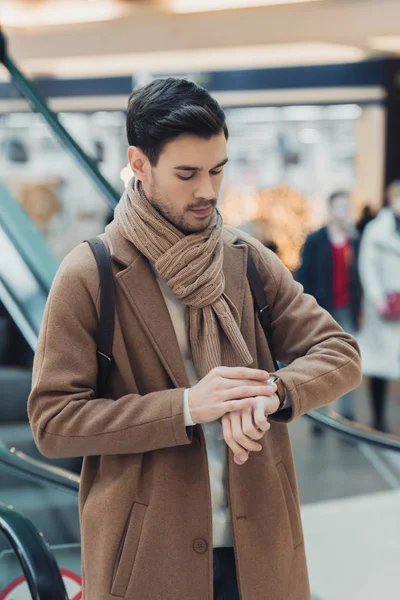 Handsome man looking at watch in shopping mall — Stock Photo