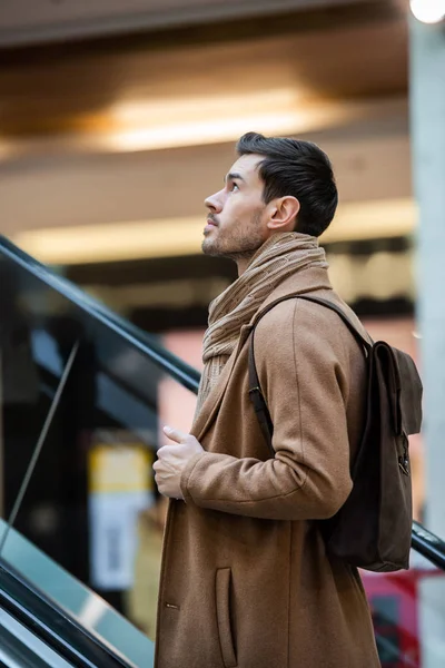 Handsome man going up on escalator in shopping mall — Stock Photo