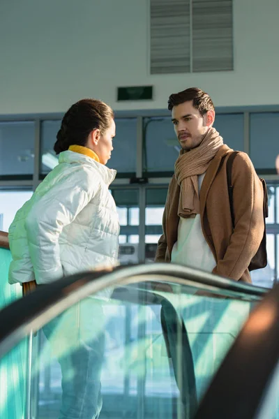 Bel homme regardant petite amie au sommet de l'escalator — Photo de stock