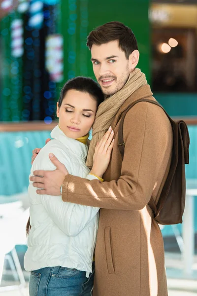 Handsome man embracing girlfriend, smiling and looking at camera — Stock Photo