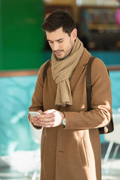 Homem bonito em roupas quentes usando smartphone — Fotografia de Stock
