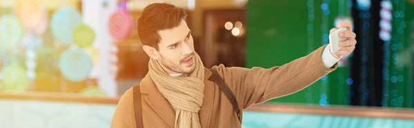 Ausgeschnittene Ansicht eines gutaussehenden Mannes in warmer Kleidung, der ein Selfie macht — Stockfoto