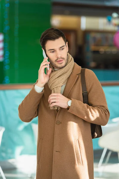 Разочарованный мужчина в теплой одежде разговаривает на смартфоне — стоковое фото