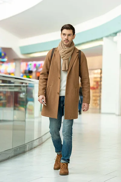Bel homme avec smartphone dans le centre commercial — Photo de stock