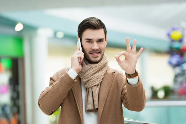 Schöner Mann spricht auf Smartphone und zeigt ok Zeichen — Stockfoto