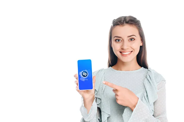 Mujer sonriente mostrando el teléfono inteligente con el logotipo de shazam en la pantalla aislada en blanco - foto de stock