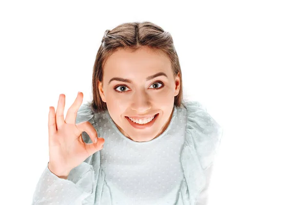 Vista ad alto angolo di attraente donna sorridente mostrando segno ok isolato su bianco — Foto stock