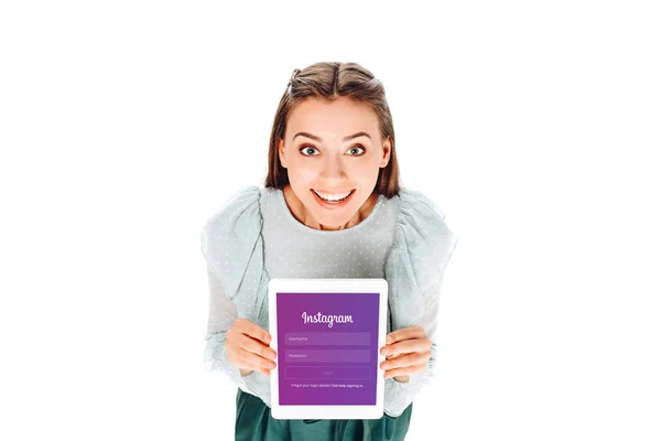 Высокий угол зрения улыбающейся женщины с планшетом с логотипом Instagram на экране изолированы на белом — стоковое фото