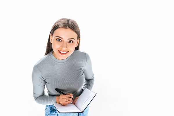 Visão de alto ângulo da mulher sorridente com notebook e caneta isolada em branco — Fotografia de Stock