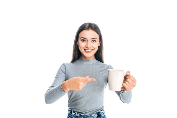 Portrait of young woman pointing at cup of coffee isolated on white — Stock Photo