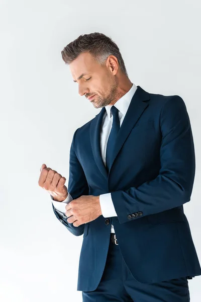 Bajo ángulo vista de guapo hombre de negocios abotonamiento manguito aislado en blanco - foto de stock