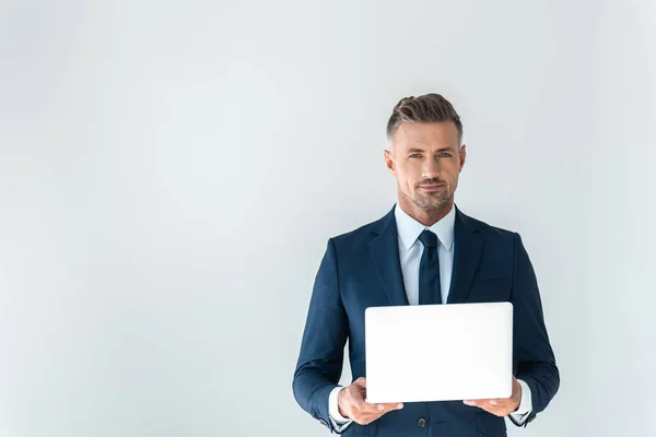 Guapo hombre de negocios sosteniendo portátil y mirando a la cámara aislada en blanco - foto de stock