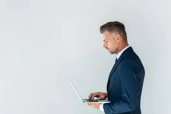 Вид збоку красивого бізнесмена з використанням ноутбука ізольовано на білому — Stock Photo