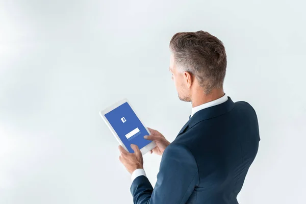 Vista ad alto angolo di uomo d'affari in possesso di tablet con pagina facebook isolato su bianco — Foto stock