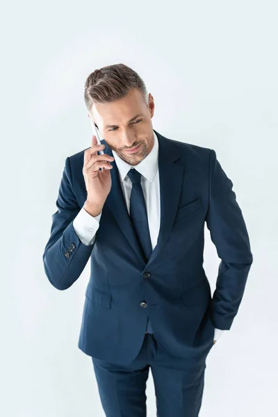 Vista de ángulo alto de hombre de negocios guapo en traje azul hablando por teléfono inteligente aislado en blanco - foto de stock