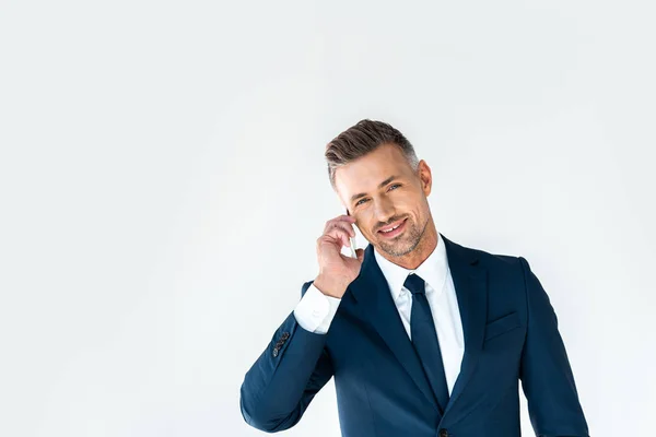 Sonriente hombre de negocios guapo hablando por teléfono inteligente y mirando la cámara aislada en blanco - foto de stock