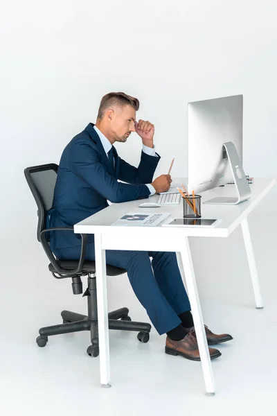 Visão lateral de empresário bonito sério olhando para o computador isolado no branco — Fotografia de Stock