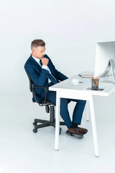 Вид сбоку застенчивого красавца-бизнесмена, смотрящего на компьютер, изолированный от белого — стоковое фото
