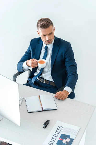 Vista de ángulo alto de hombre de negocios guapo sosteniendo taza de café aislado en blanco - foto de stock